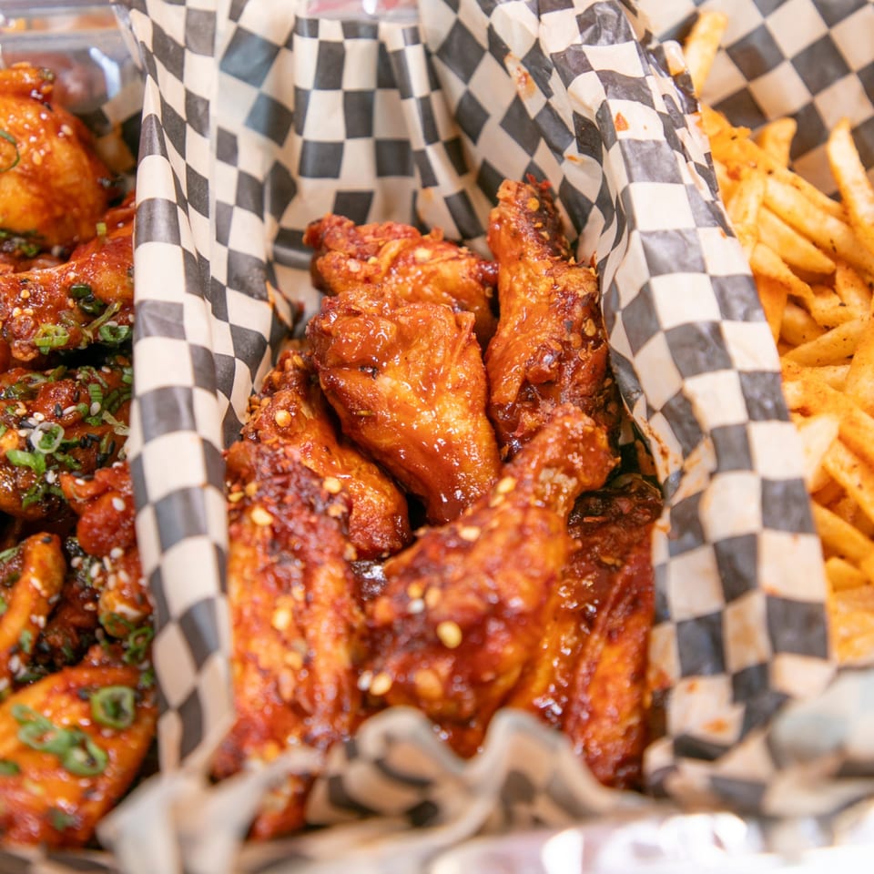 Three baskets of Knockout Wings, two with saucy chicken wings and one with golden french fries.